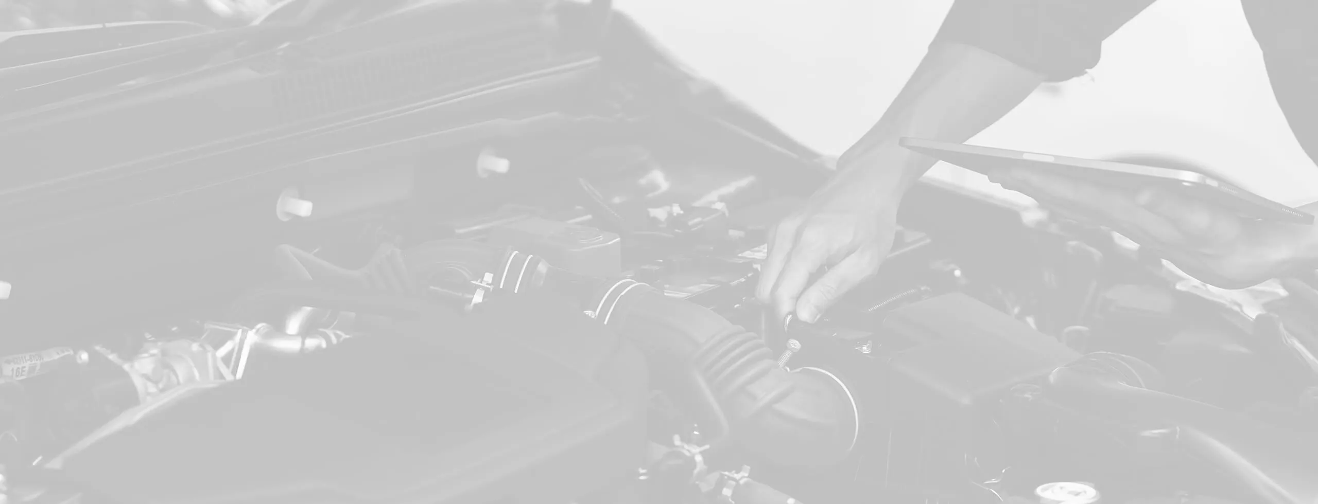 Mechanic inspecting car engine with tablet.