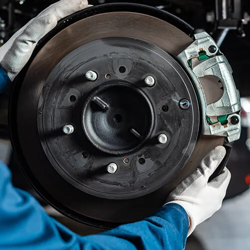 Mechanic inspecting car brake rotor and disc.